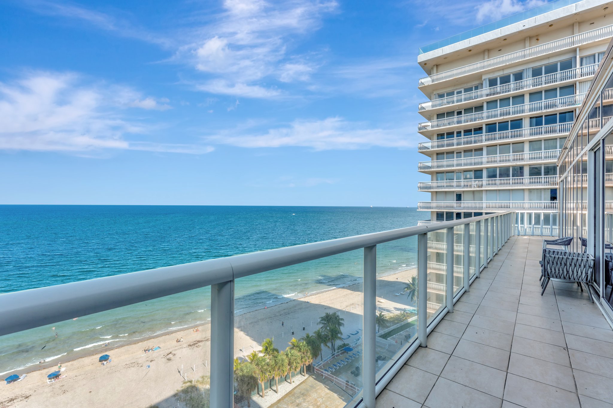 View from Penthouse 1002 balcony overlooking the beach, umbrellas, and surrounding buildings