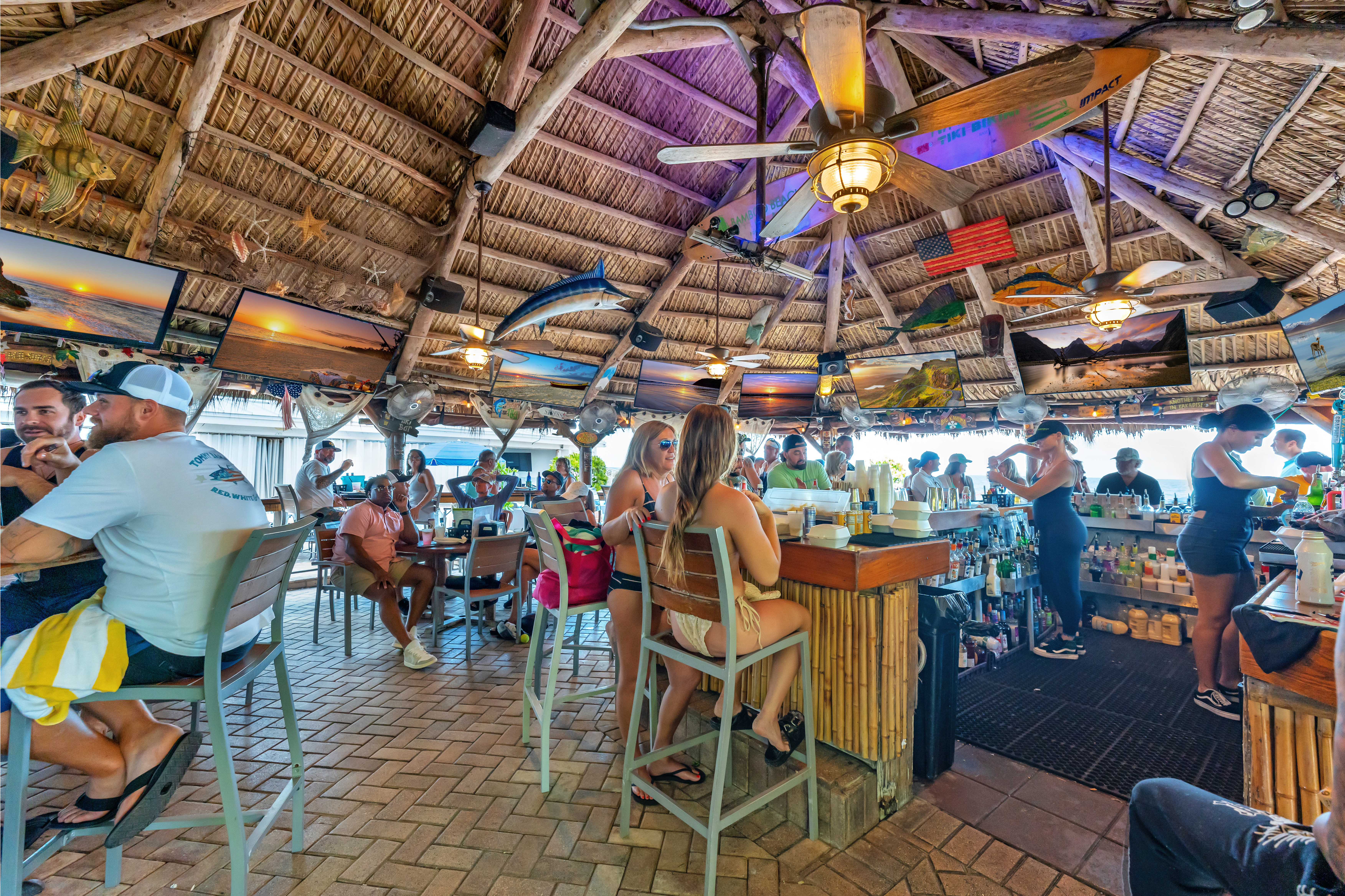 Tiki bar counter with guests and bartenders at Ocean Manor